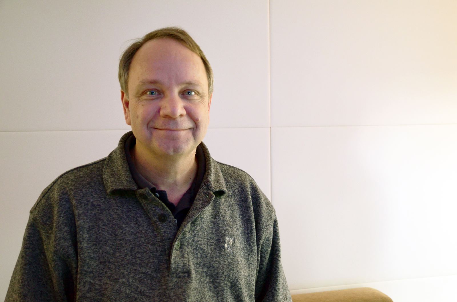 Game designer Sid Meier smiling in a grey zip sweater against a plain wall