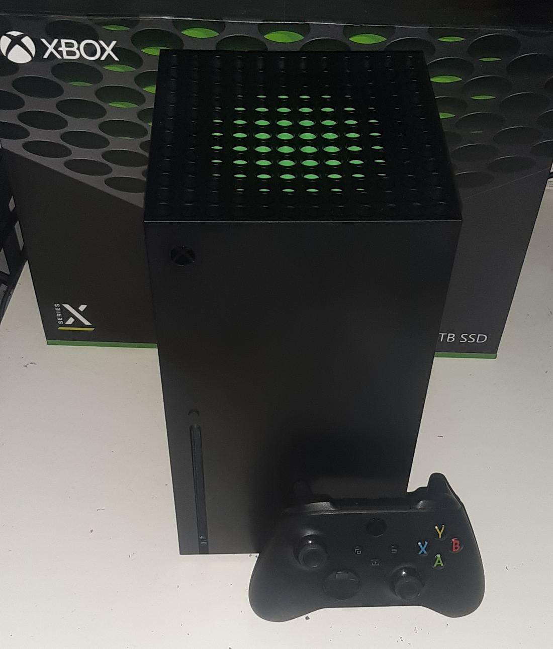 A black Xbox Series X tower console with a matching controller in front of it
